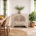 Lifestyle image of a hand carved mango wood cabinet with carved tree design on front, 90 × 80 × 40 cm, white washed.