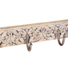 Close up image of a hand-carved reclaimed wood wall hook rack crafted from an antique Indian architectural element with five iron hooks, intricate floral carvings, bleached finish, and vintage rustic character, 150cm.