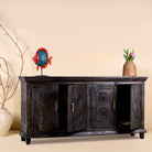 Side angle image with open doors of a handcrafted wood carved sideboard in black mango wood with four doors, versatile for bedroom furniture or living spaces, 180 × 40 × 90 cm.