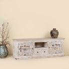 Side angle image of a old door cabinet with hand-carved antique teak panels, whitewashed mango wood body, drawers and shelf, 180 × 40 × 70 cm.