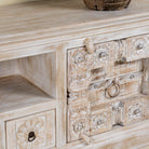 Close up picture of a old door cabinet with hand-carved antique teak panels, whitewashed mango wood body, drawers and shelf, 180 × 40 × 70 cm.