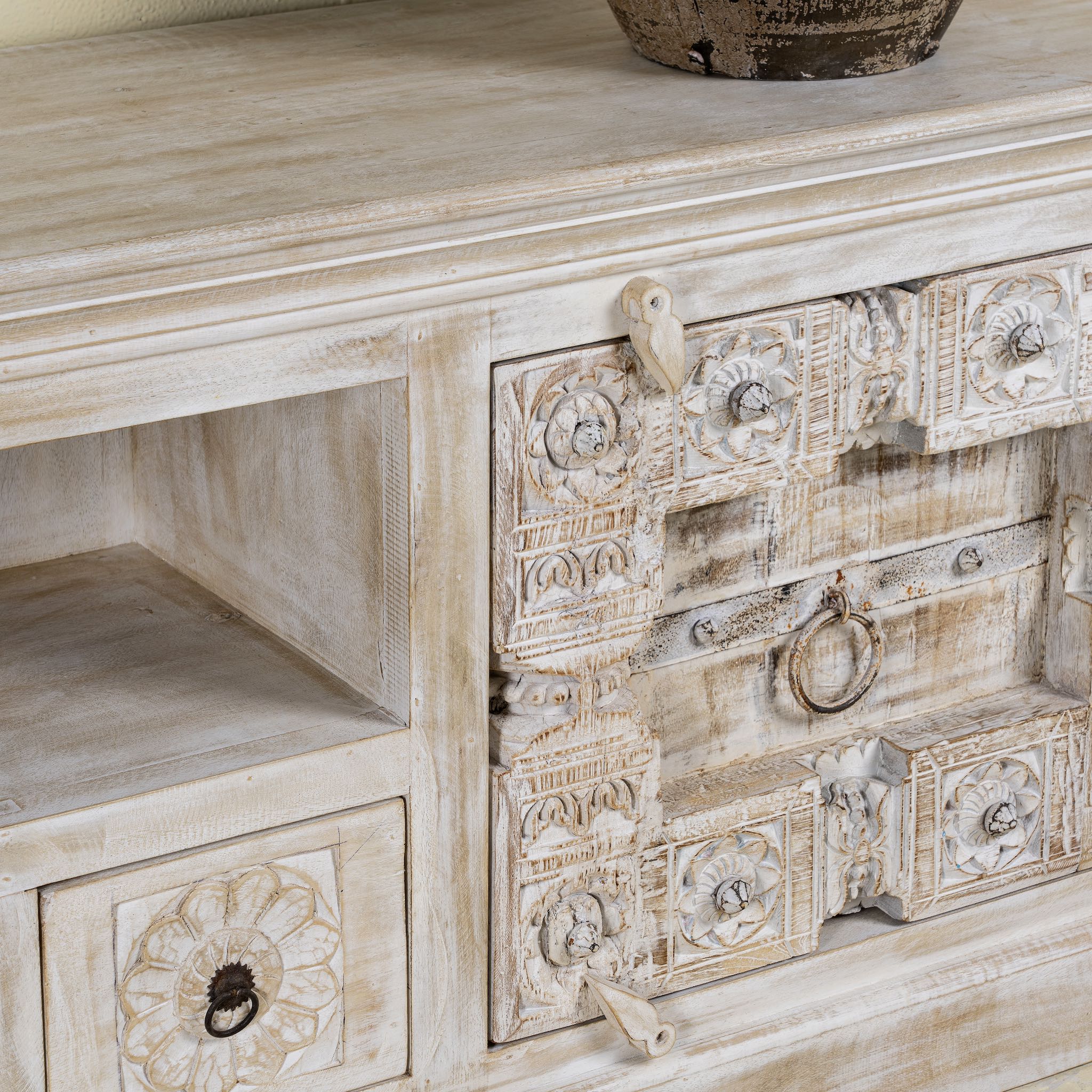 Close up picture of a old door cabinet with hand-carved antique teak panels, whitewashed mango wood body, drawers and shelf, 180 × 40 × 70 cm.