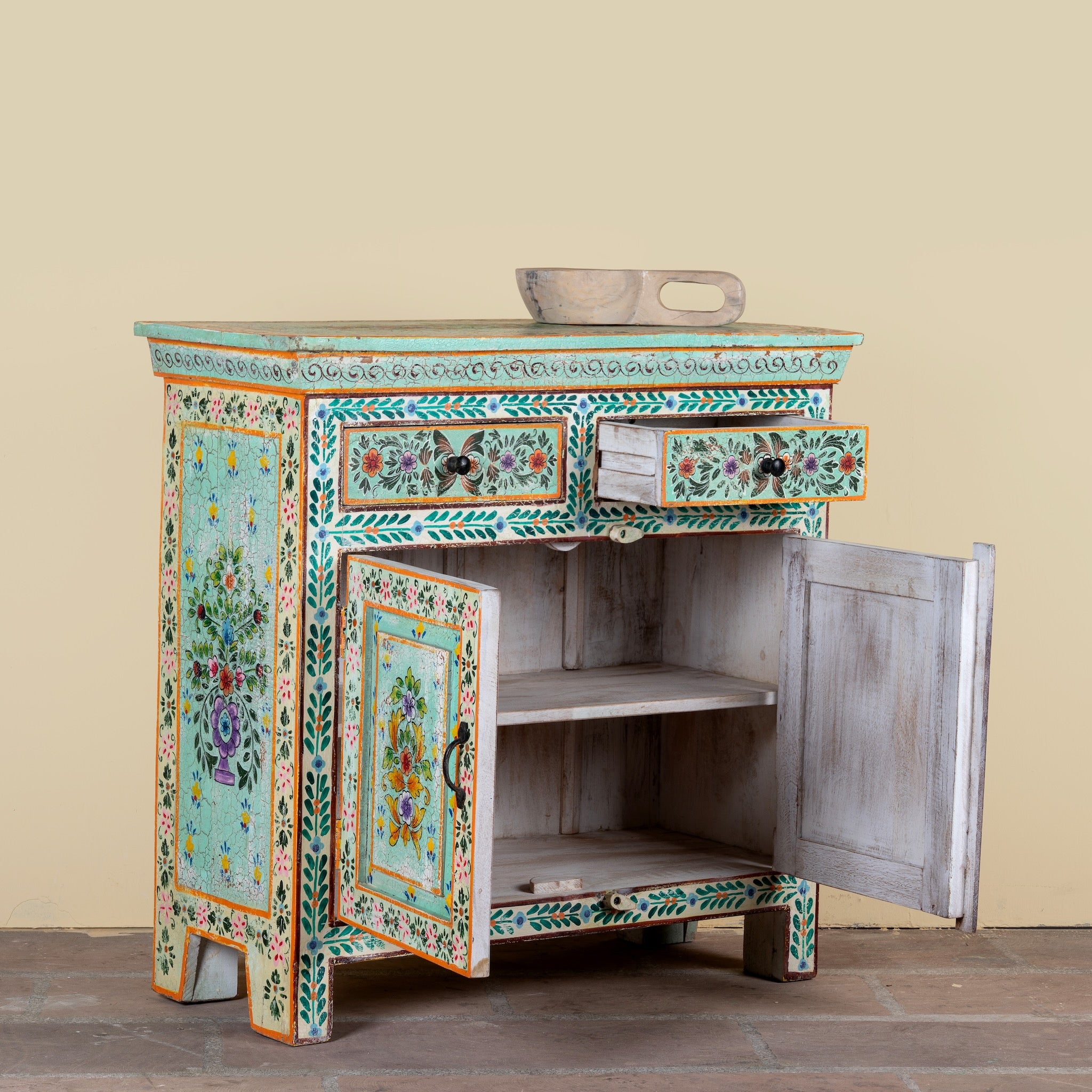 Side angle image with open doors of a hand painted green Indian cabinet made from recycled wood with floral motifs, 2 drawers and 2 compartments, 90 × 90 × 40 cm.