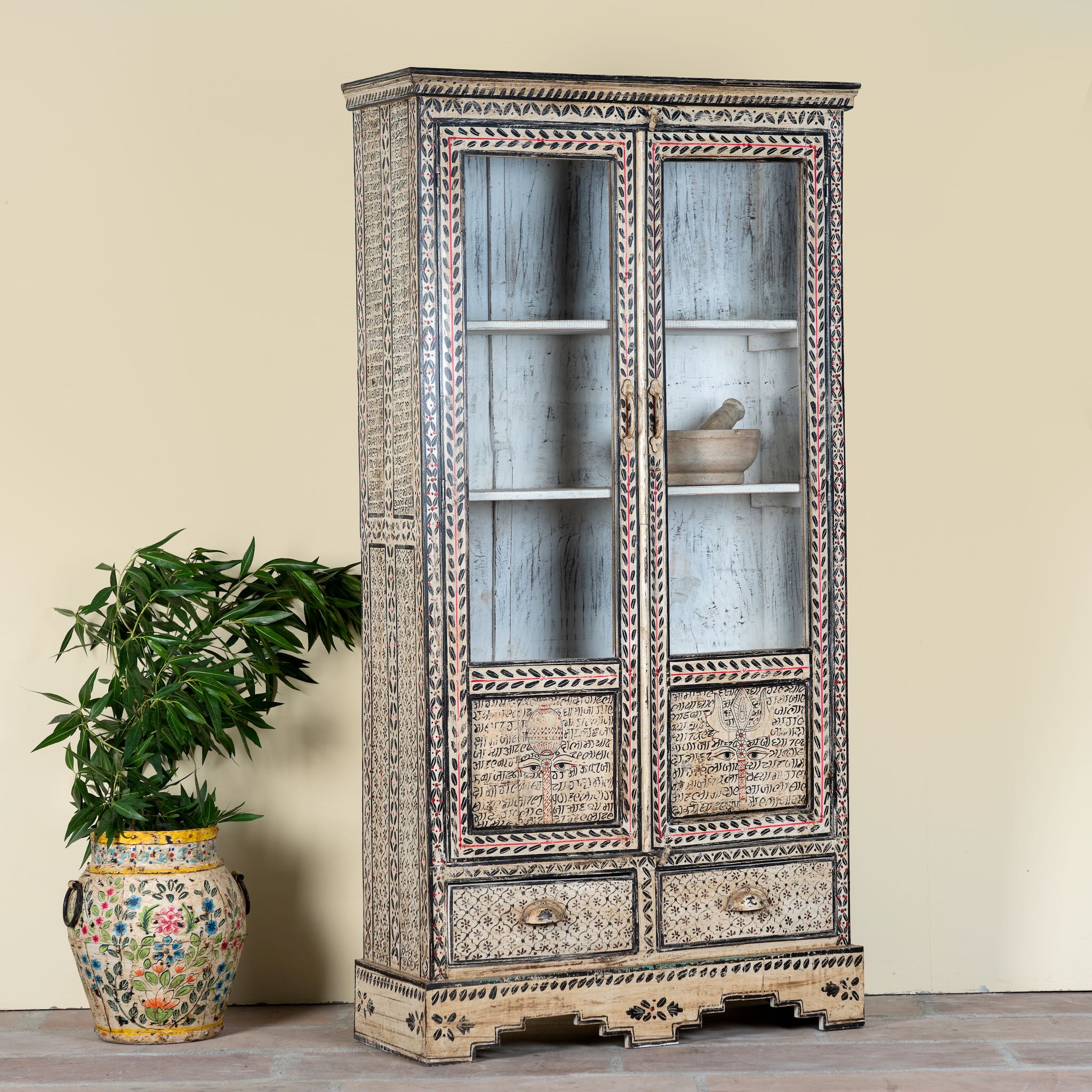 Side angle image of a hand-painted display cabinet Ritesh made from recycled wood with glass doors – sustainable furniture featuring Sanskrit motifs and traditional Indian craftsmanship.