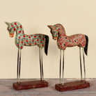 Ritish hand-painted wooden horse sculptures on iron stands in assorted colours and designs. Unique Indian decor items, perfect for bohemian interiors and artisanal furniture displays.
