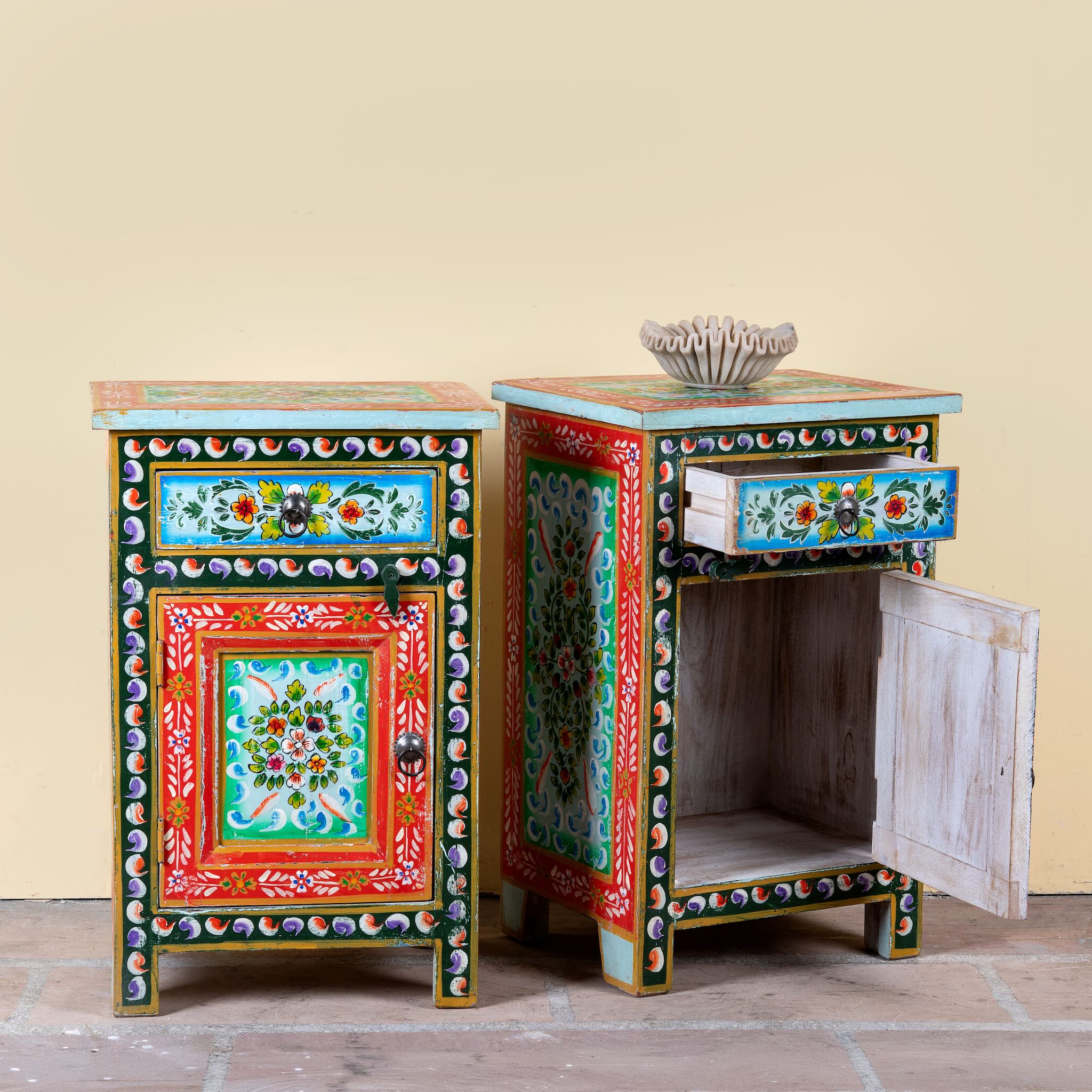 Side angle image with open drawer and door of a hand-painted bedside table made from recycled wood – vintage night stands with carved mango wood furniture detailing and floral artistry.
