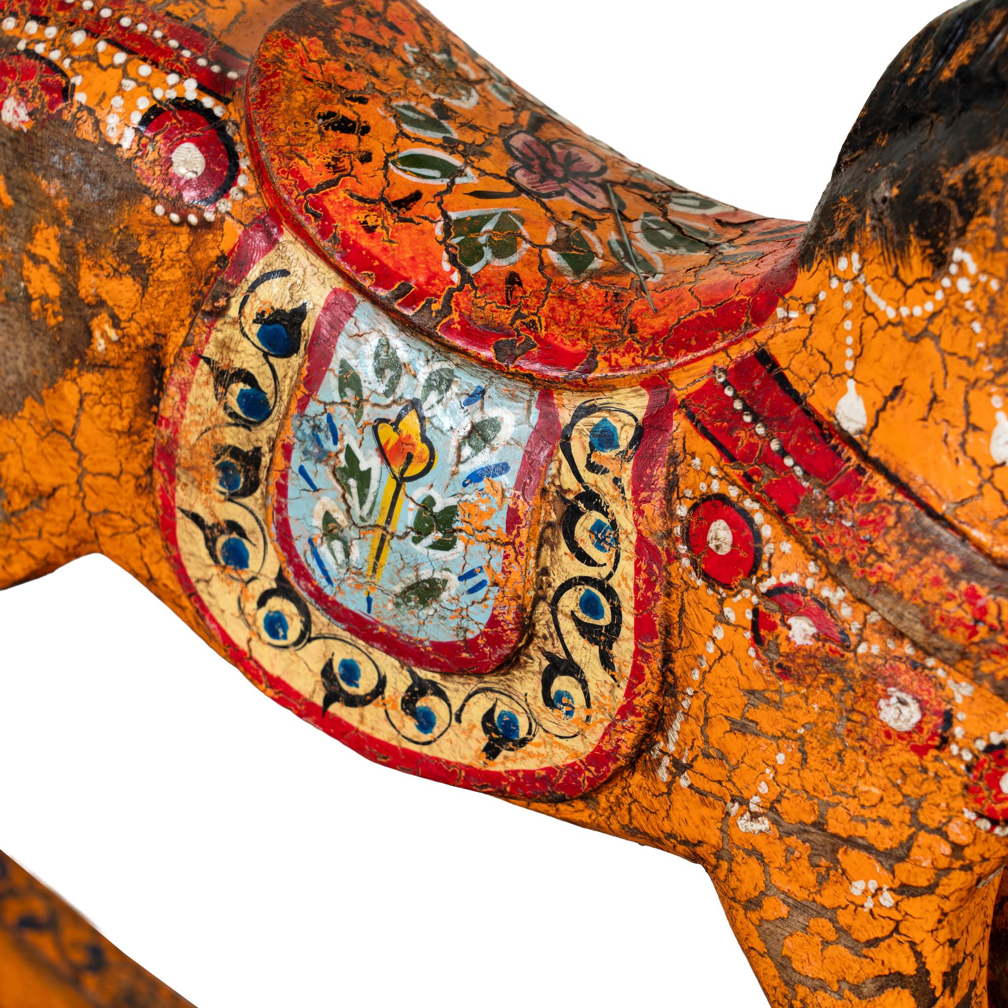 Close up image of a colourful hand-painted wooden rocking horses with ornate saddle patterns, crafted in India. Unique bohemian interior décor accents made from solid wood, perfect for shelves or sideboards.