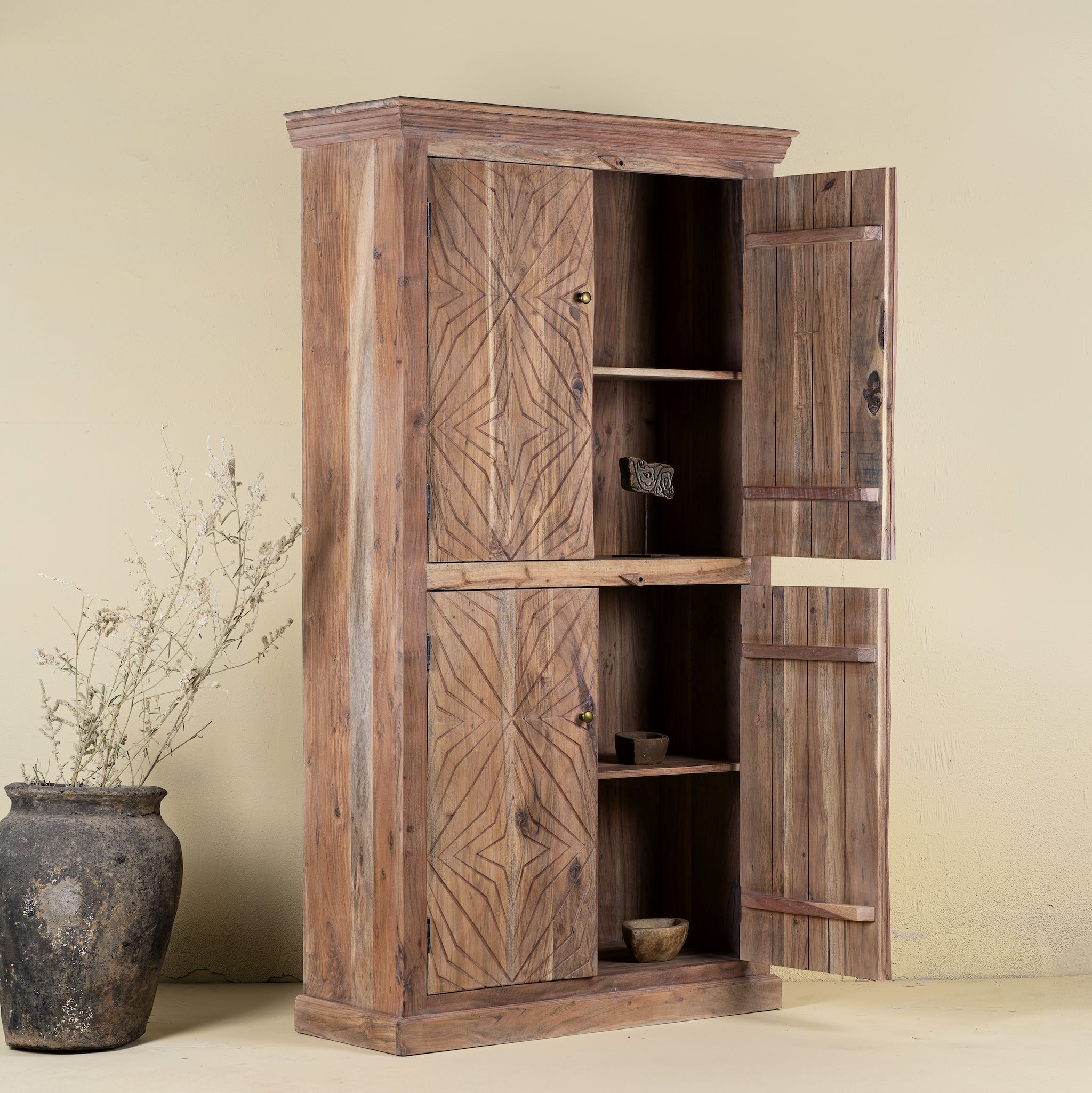 Open door view of a carved acacia wood wardrobe with floral detailing and brass handles; artisanal acacia wood furniture, 100 × 40 × 180 cm.