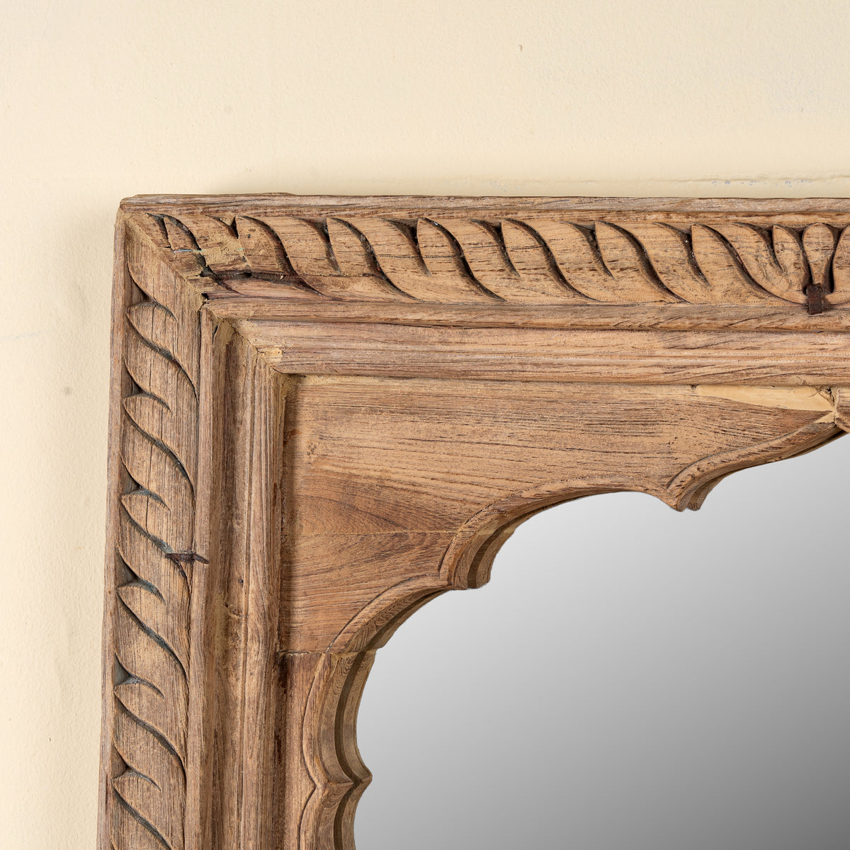 Close up image of a Ronavraj reclaimed teak wood mirror made from an old Indian window frame with carved border and shaped arch, 82x121cm