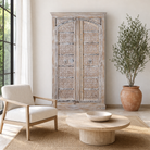 Lifestyle image of a handcrafted carved wood wardrobe with whitewashed finish and arched teak doors – Ruchi by Om Home & Garden, vintage-inspired white washed furniture with artisanal detailing.