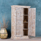 Wooden cabinet with intricate carvings on a textured blue wall