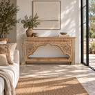 Lifestyle image of a Ruhan reclaimed teak wood console table with hand-carved Indian architectural front and open storage shelf 171cm