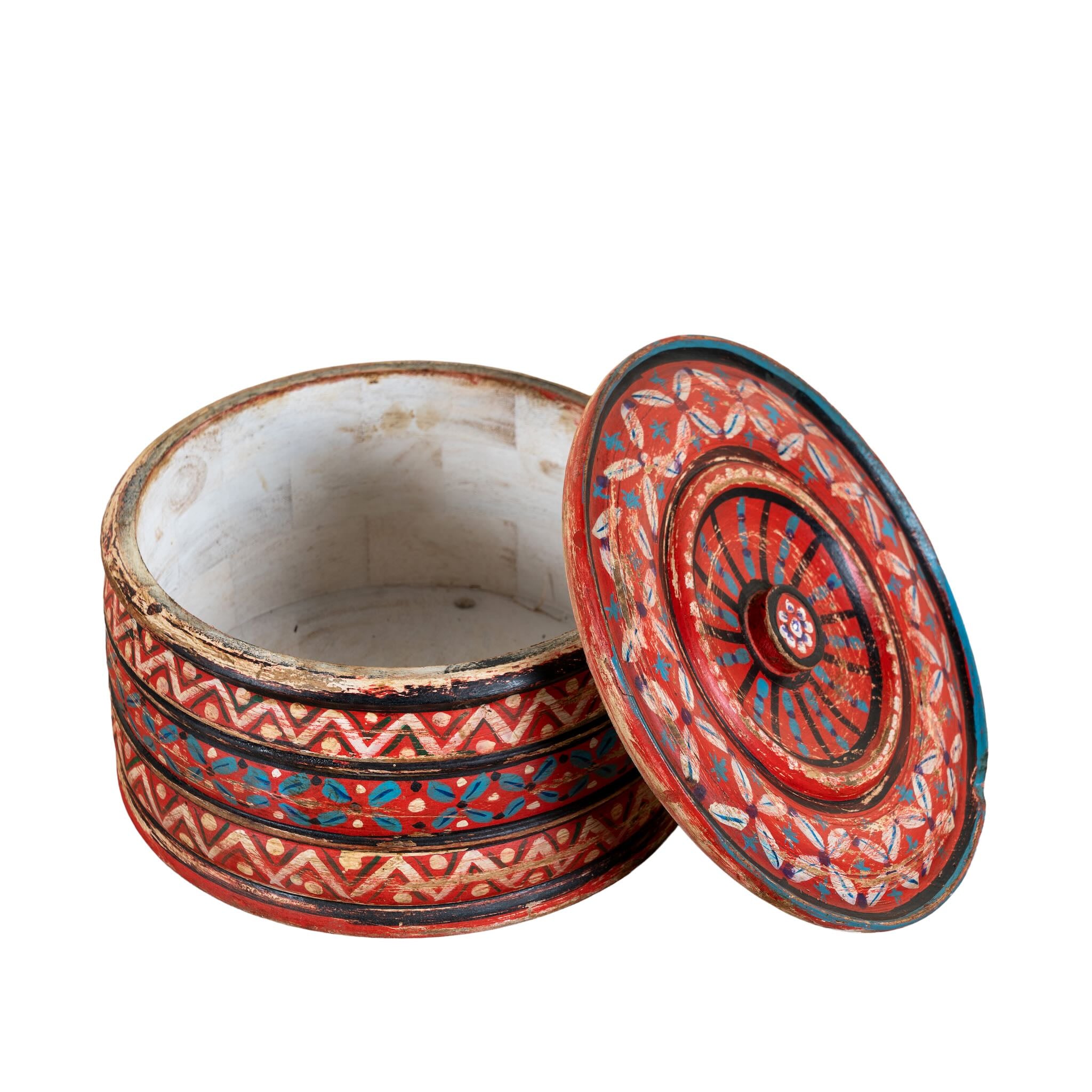 White background image of a hand-painted round wooden box with lid, featuring traditional Indian script and decorative motifs in red, blue, and black. A unique Indian decor item used for storage or display, available in four different designs.