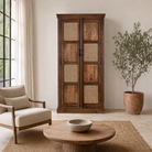 Lifestyle image of a tall mango wood furniture cabinet with hand-carved details and woven rattan doors, artisan rattan furniture, 90 × 40 × 180 cm.