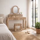 Lifestyle image of a of a handcrafted mango wood cosmetic table with a curved mirror and matching stool, showcasing a vintage style with a beige finish.