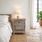 Lifestyle image of a vintage style nightstand made of reclaimed wood with one drawer and storage.