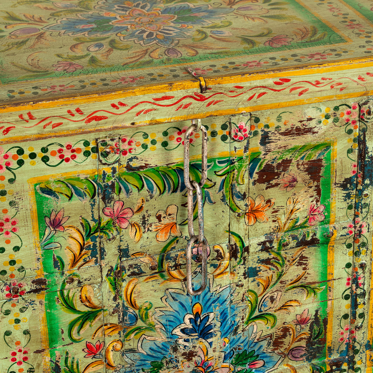 Close up image of a Ruturaj hand painted reclaimed Indian teak wood chest with colourful floral motifs and iron fittings 150cm