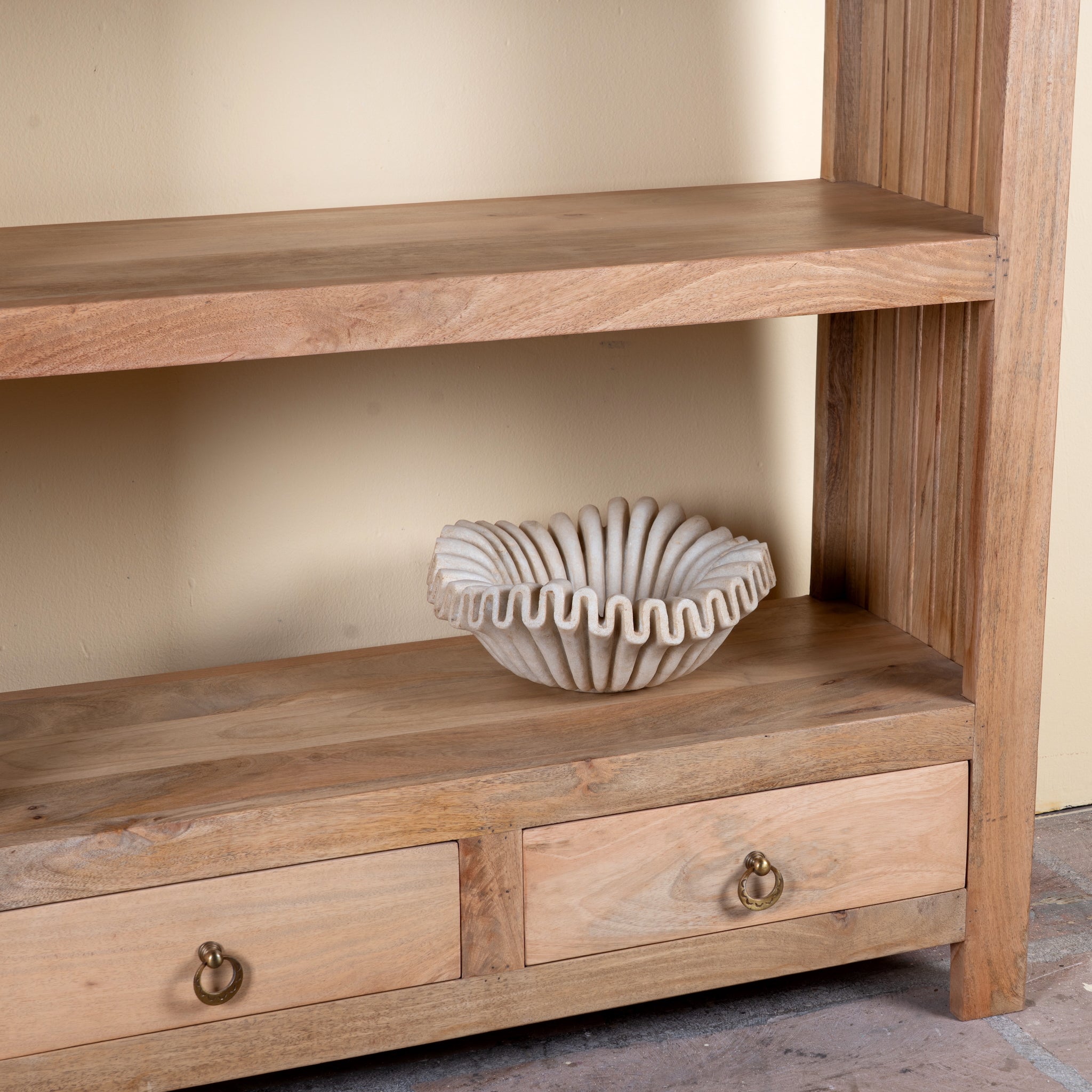 Close up image of a Sahadev wide mango wood shelving unit with open shelves and two drawers 190cm