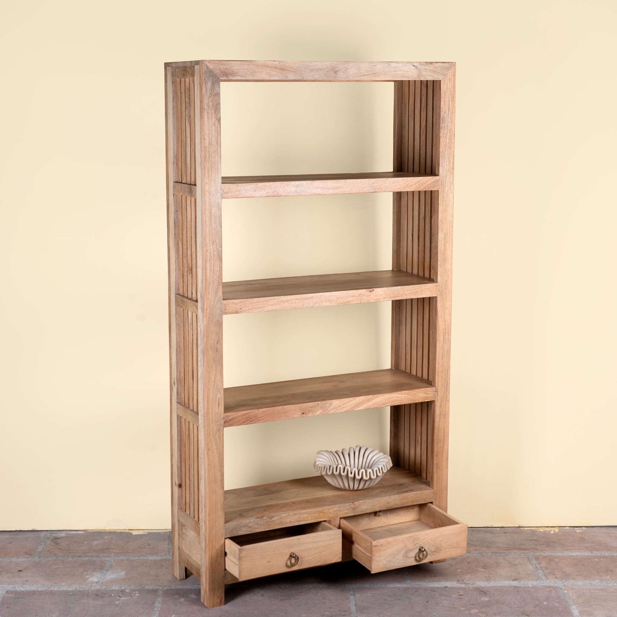 Side angle image of a Sahadev wide mango wood shelving unit with open shelves and two drawers 190cm