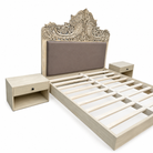 Side angle image of a hand-carved vintage bed Samar made from distressed mango wood, featuring an ornate high headboard with soft grey fabric upholstery. A unique blend of Indian craftsmanship and contemporary comfort in a natural, neutral palette.