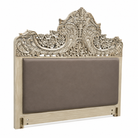Close up image of a hand-carved vintage bed Samar made from distressed mango wood, featuring an ornate high headboard with soft grey fabric upholstery. A unique blend of Indian craftsmanship and contemporary comfort in a natural, neutral palette.