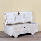 Side angle image showing open lid of a Samay mango wood storage chest coffee table with carved geometric front, iron fittings, wooden wheels and distressed finish 120cm