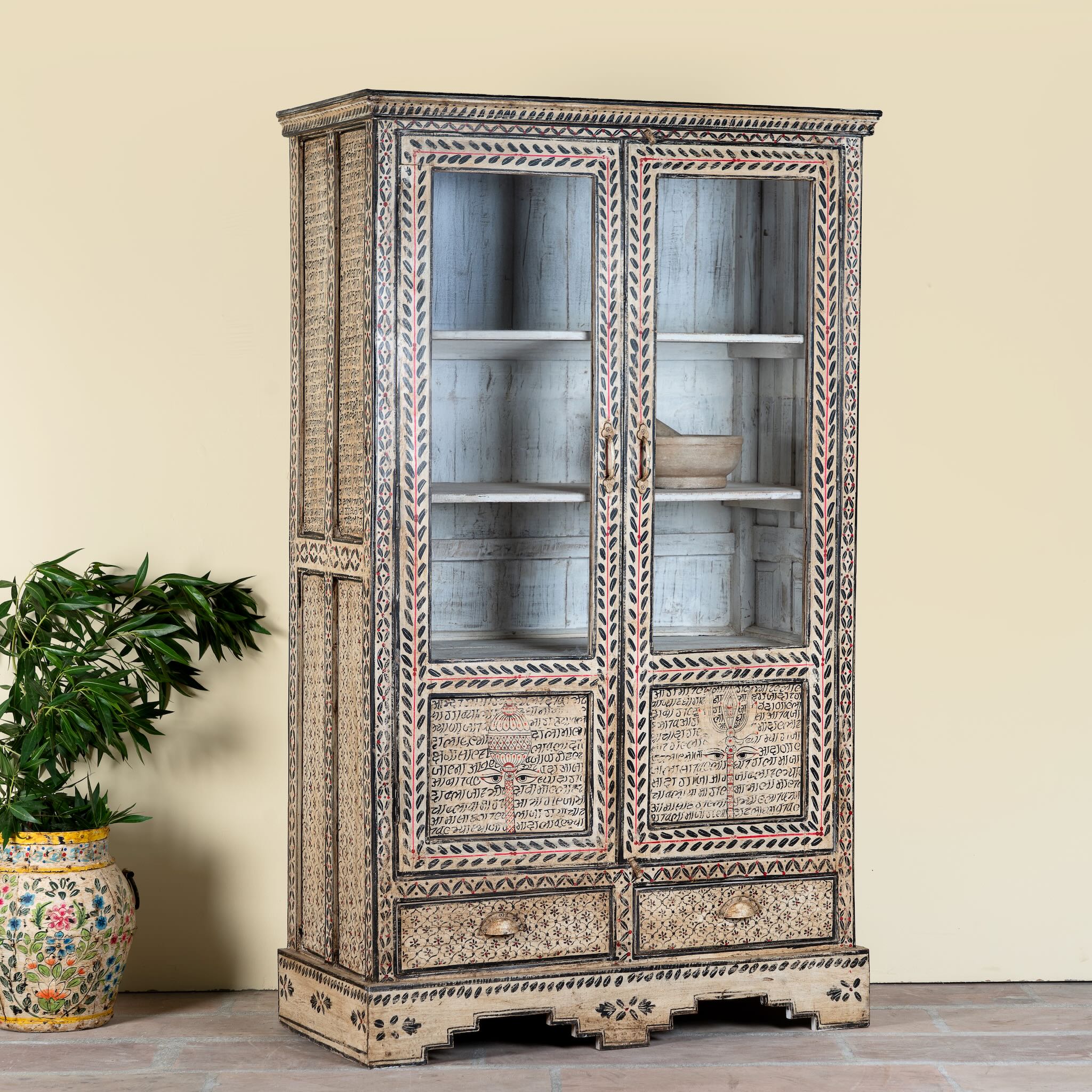 Side angle image of a of a hand-painted display cabinet Sambalpur made from recycled wood with glass doors – sustainable furniture featuring Sanskrit motifs and traditional Indian craftsmanship.