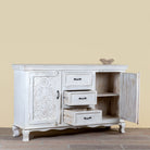Side angle image with open doors of a mediterranean-style carved sideboard in solid mango wood with floral motifs and elegant legs; ideal for vintage home decor, 150 × 90 × 40 cm.