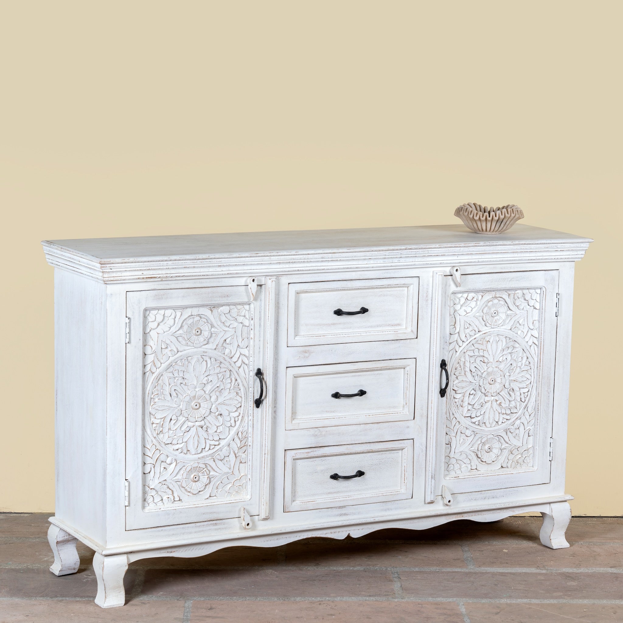 Side angle image of a mediterranean-style carved sideboard in solid mango wood with floral motifs and elegant legs; ideal for vintage home decor, 150 × 90 × 40 cm.
