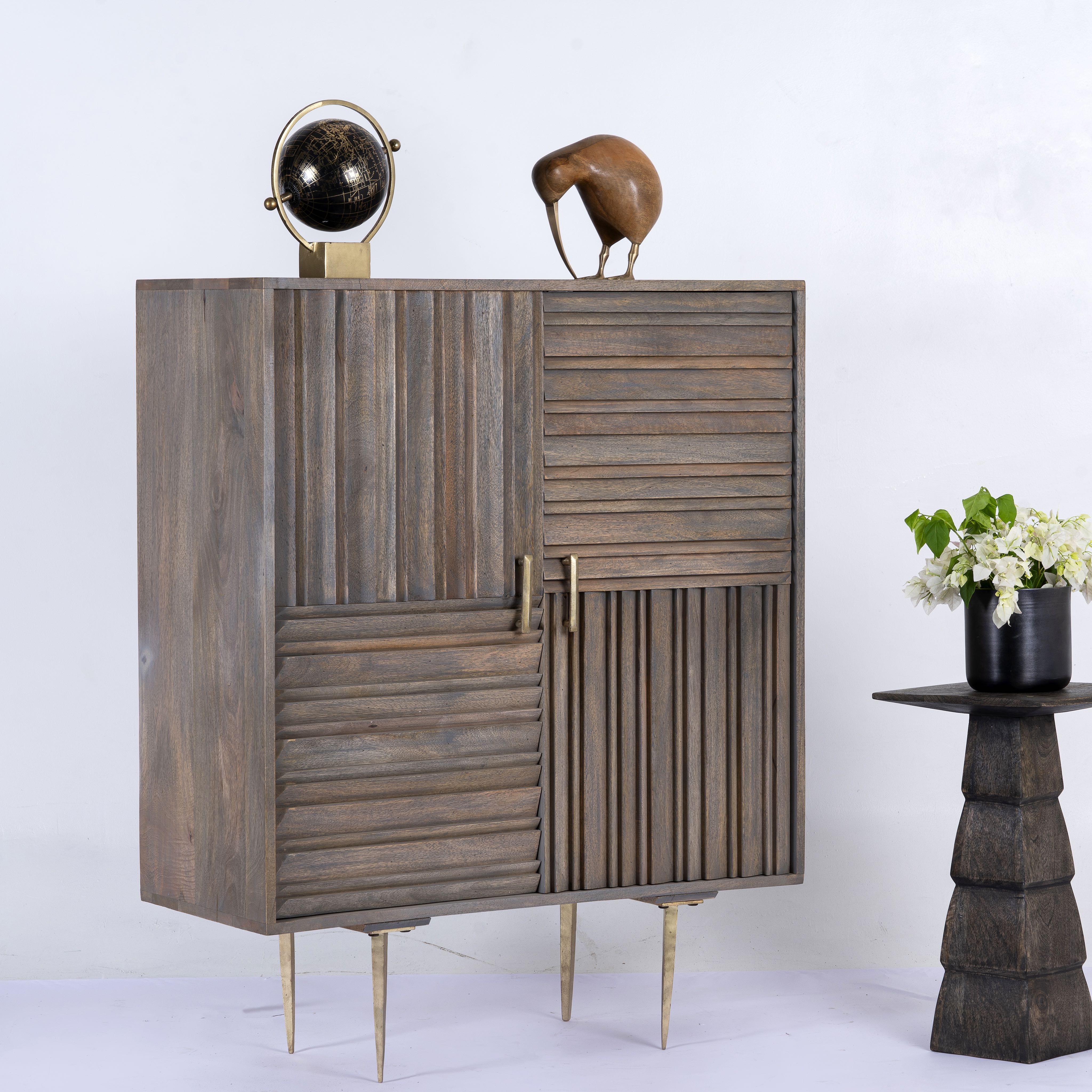 Side angle image of a grey carved cabinet in mango wood with linear carvings and brass‑plated iron base, 92 × 42 × 115 cm.