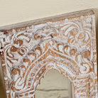 Close up image of a hand-carved wooden wall mirrors Sathvik with ornate jharokha arches and floral detailing, available in various vintage finishes. A unique Indian decoration and vintage home accessory perfect for vintage home decor settings.