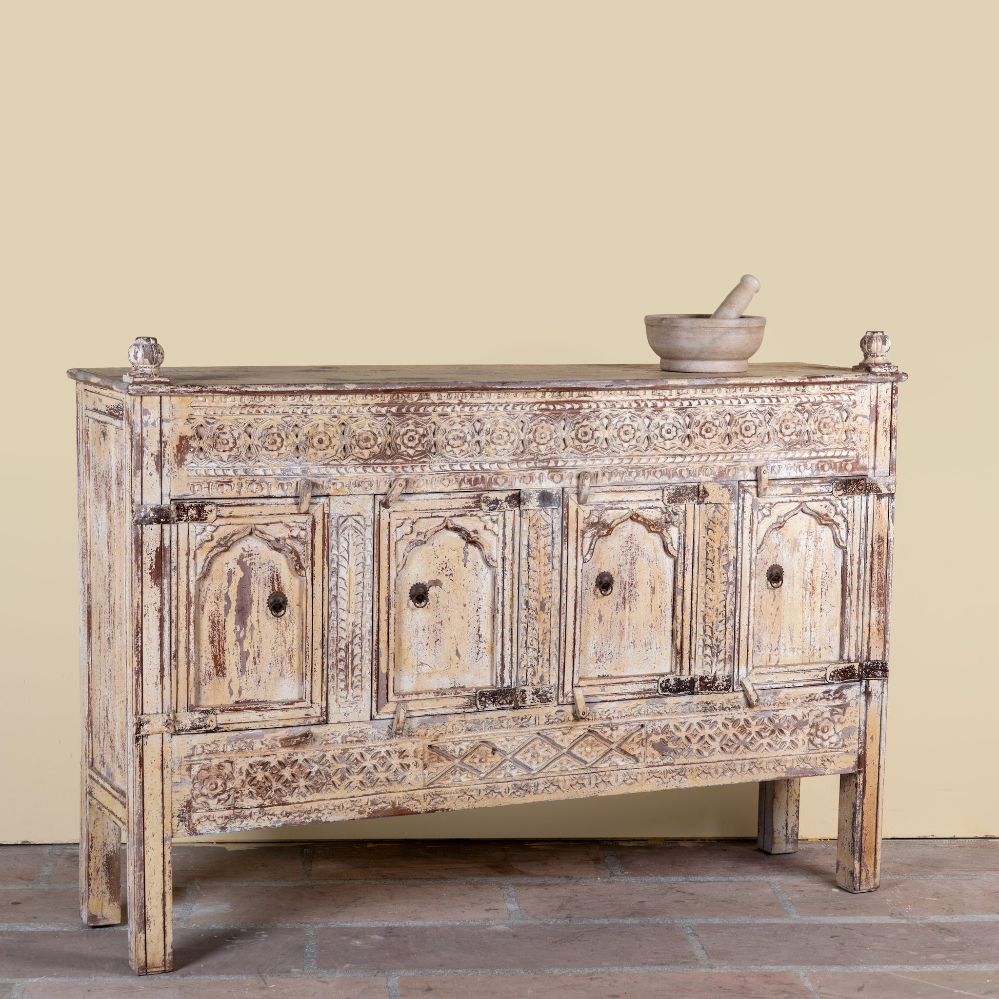 Side angle image of a Satyam hand carved reclaimed wood sideboard with four arched doors and distressed cream vintage finish 153cm
