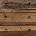 Close up image of a three-drawer dresser in Driftwood/Wabi Sabi style made from recycled old wood, featuring a naturally weathered finish with visible grain patterns and metal ring pull handles for a rustic, handcrafted look.


