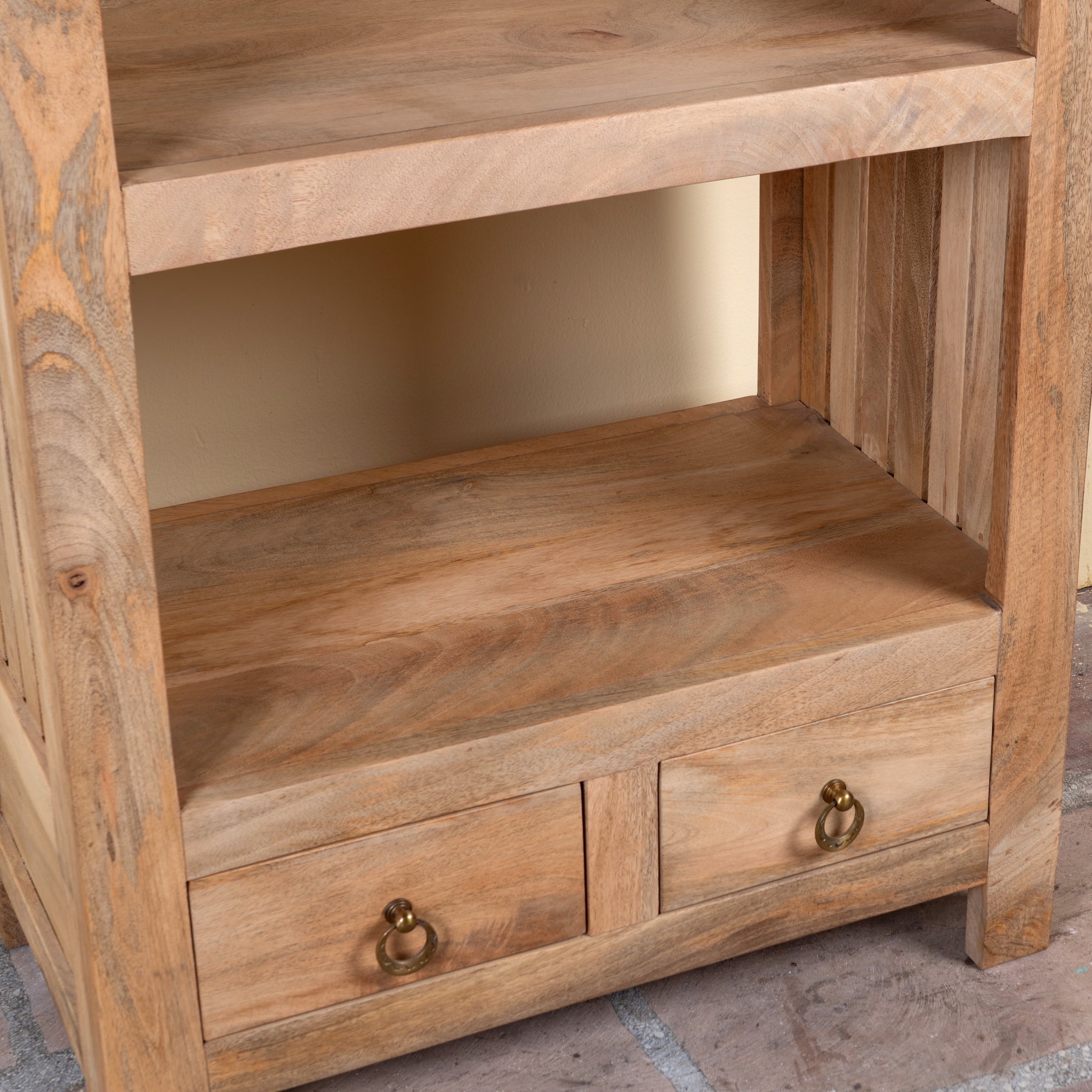 Close up image of a Shailee tall mango wood shelving unit with open shelves and two drawers 190cm