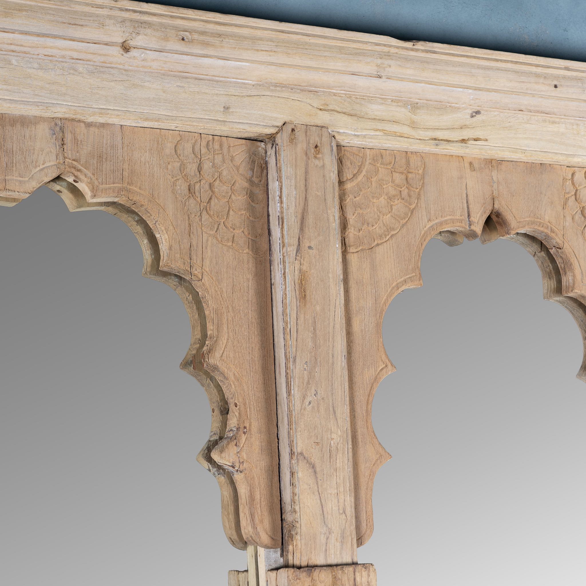 Close up image of a antique Indian arch mirror Shalee made from a reclaimed teak wood double window with carved arches. A unique piece of rustic wall art and functional décor for bohemian or vintage-inspired interiors.