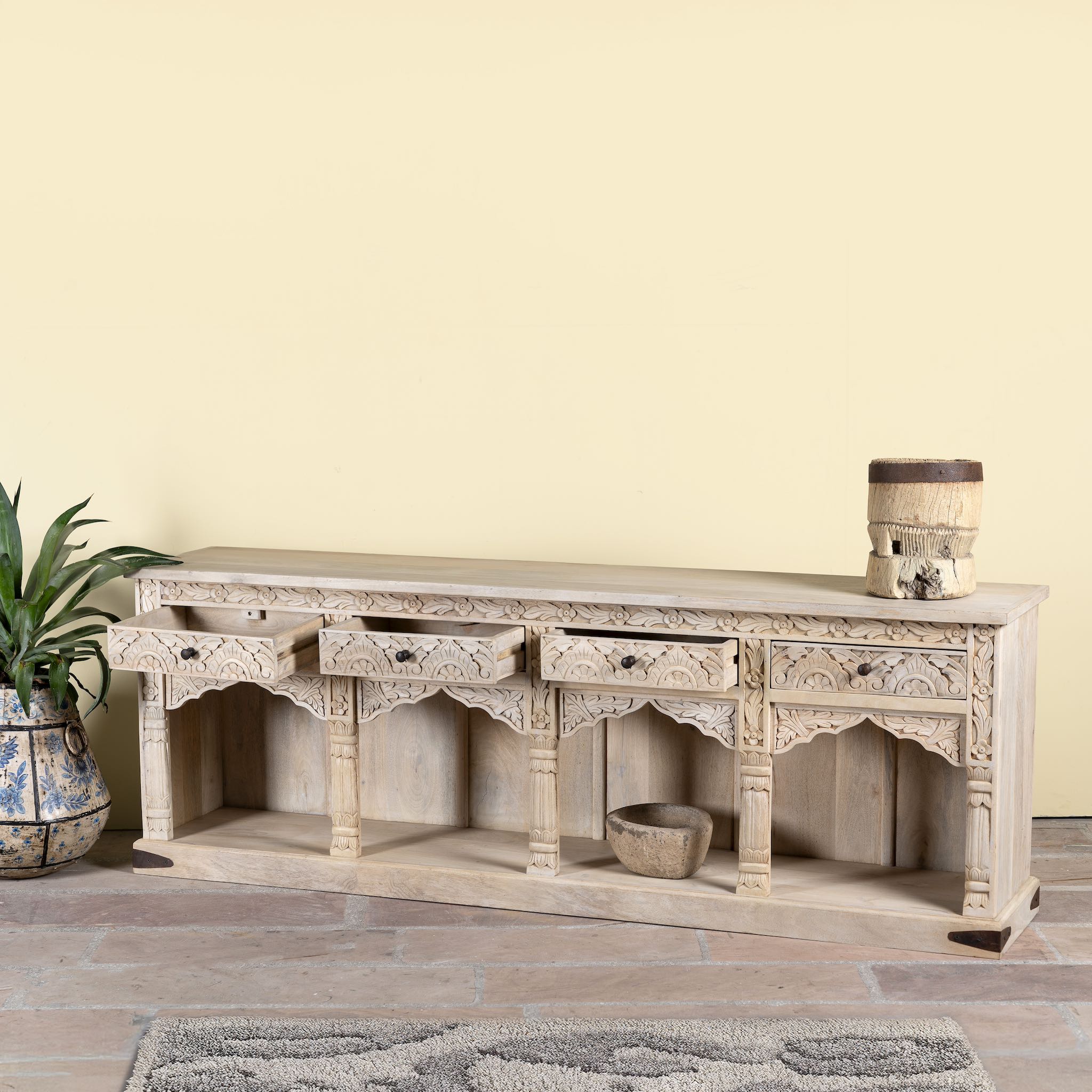 Side angle image with open drawers of a carved console table made of sandblasted mango wood with four drawers and hand-carved front; vintage entryway table, 200 × 40 × 71 cm.