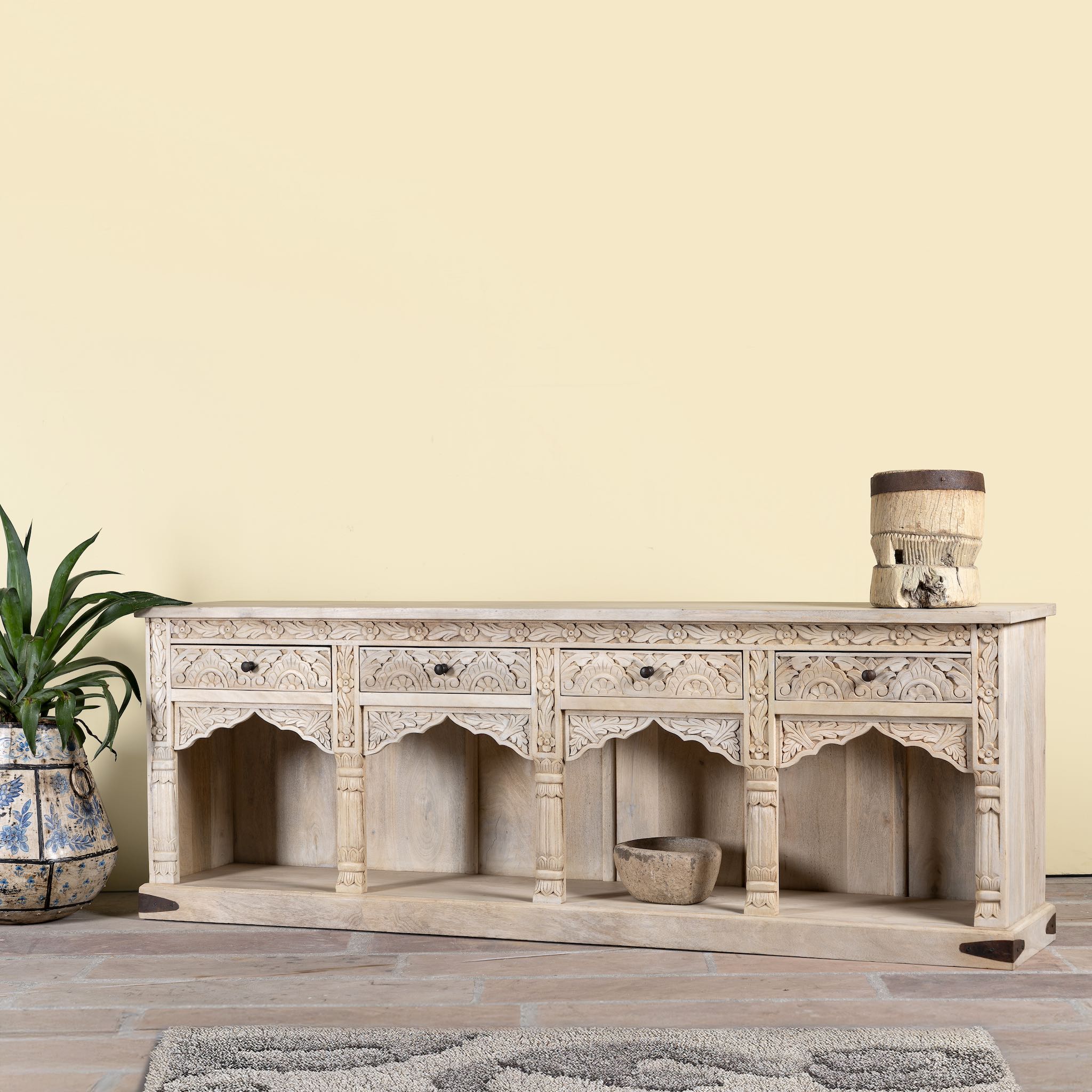 Side angle image of a carved console table made of sandblasted mango wood with four drawers and hand-carved front; vintage entryway table, 200 × 40 × 71 cm.