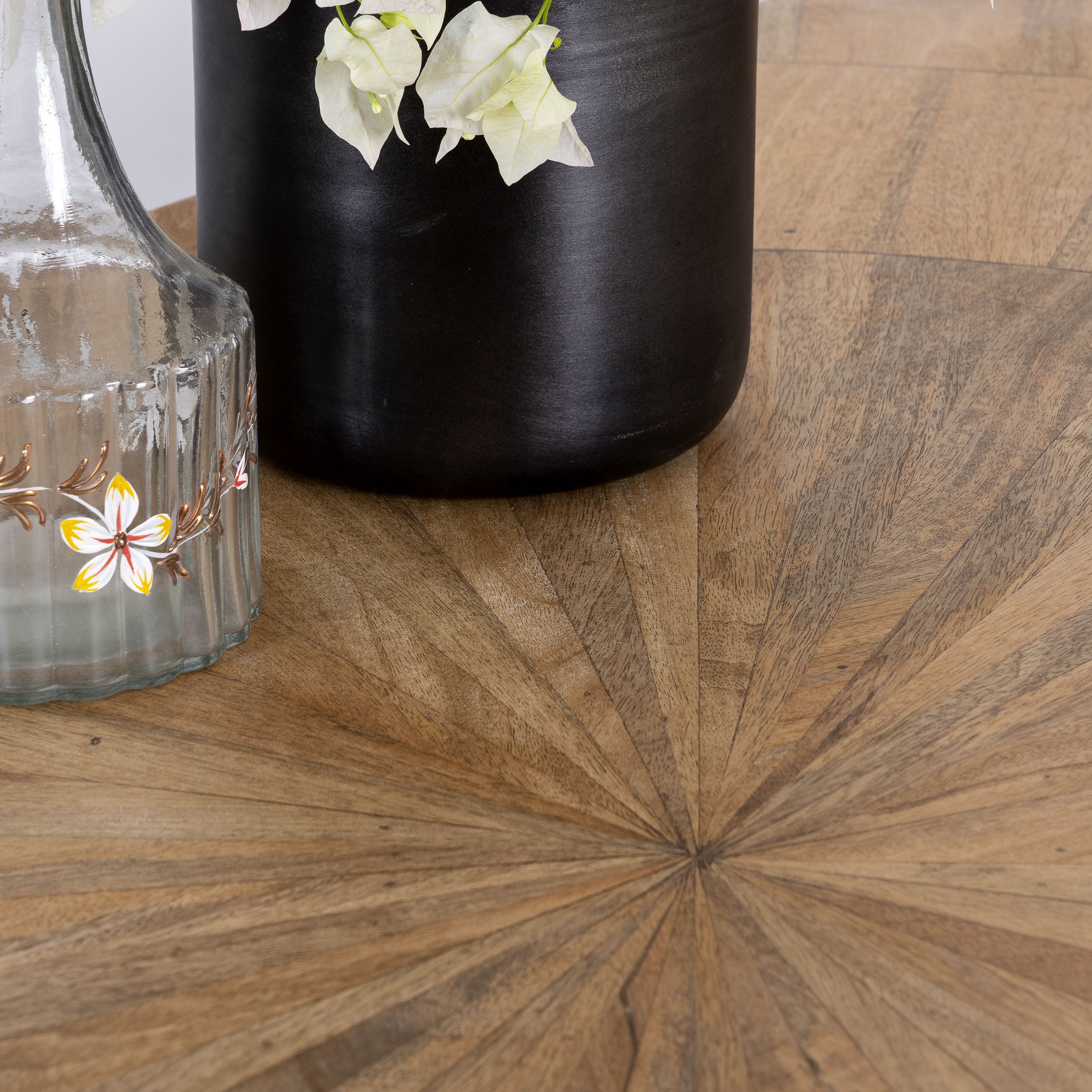 Close up image of a Shankhin mango wood dining table featuring an intricately patterned natural wood tabletop with a brass-plated iron base and contemporary industrial design, 180cm.
