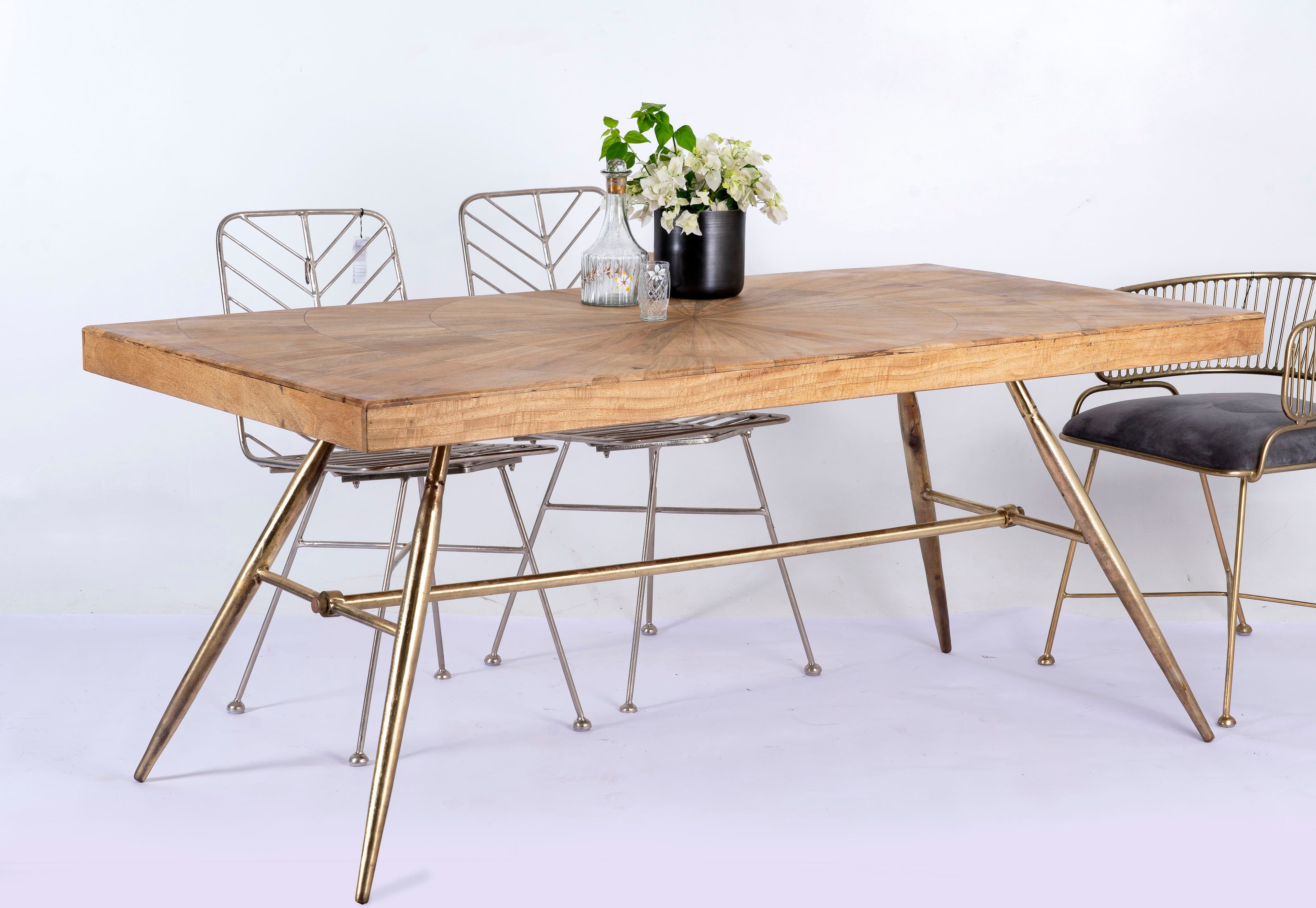 Side angle image of a Shankhin mango wood dining table featuring an intricately patterned natural wood tabletop with a brass-plated iron base and contemporary industrial design, 180cm.