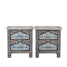 White background picture of a pair of hand-painted nightstands made from reclaimed wood, featuring floral motifs in soft turquoise and black with intricate carved detailing and two drawers for storage.

