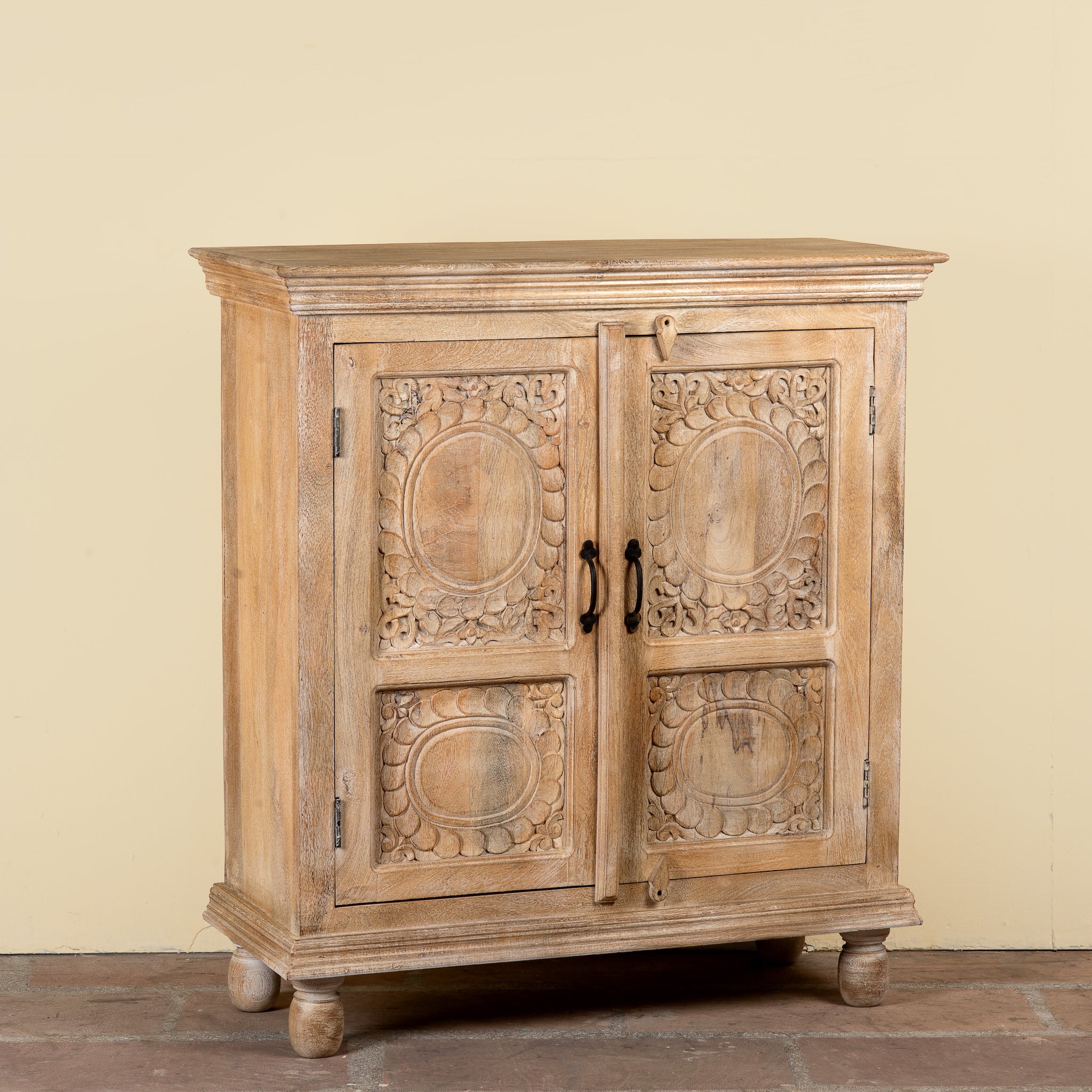 Side angle image of a Sharad hand-carved reclaimed wood cabinet with two carved doors and natural aged wood character.