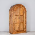 Side angle image of a Shivaaya hand carved mango wood cabinet with geometric double doors and arched top 210cm