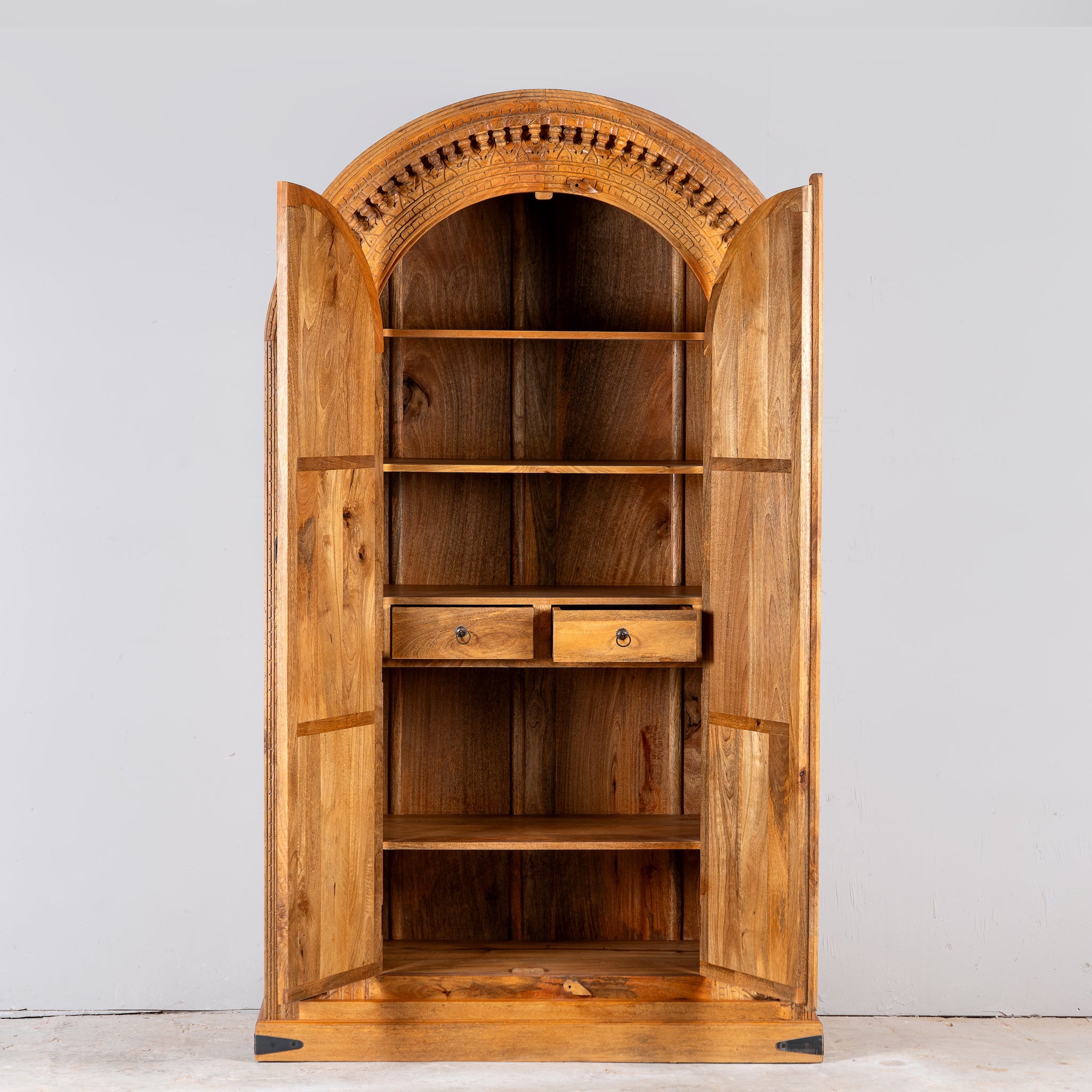 Image showing open doors of a Shivaaya hand carved mango wood cabinet with geometric double doors and arched top 210cm