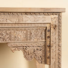 Close up image of a Shivam hand carved reclaimed teak wood console table with decorative old Indian house elements and open storage shelf, 132cm wide.