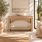 Lifestyle image of a Shivam hand carved reclaimed teak wood console table with decorative old Indian house elements and open storage shelf, 132cm wide