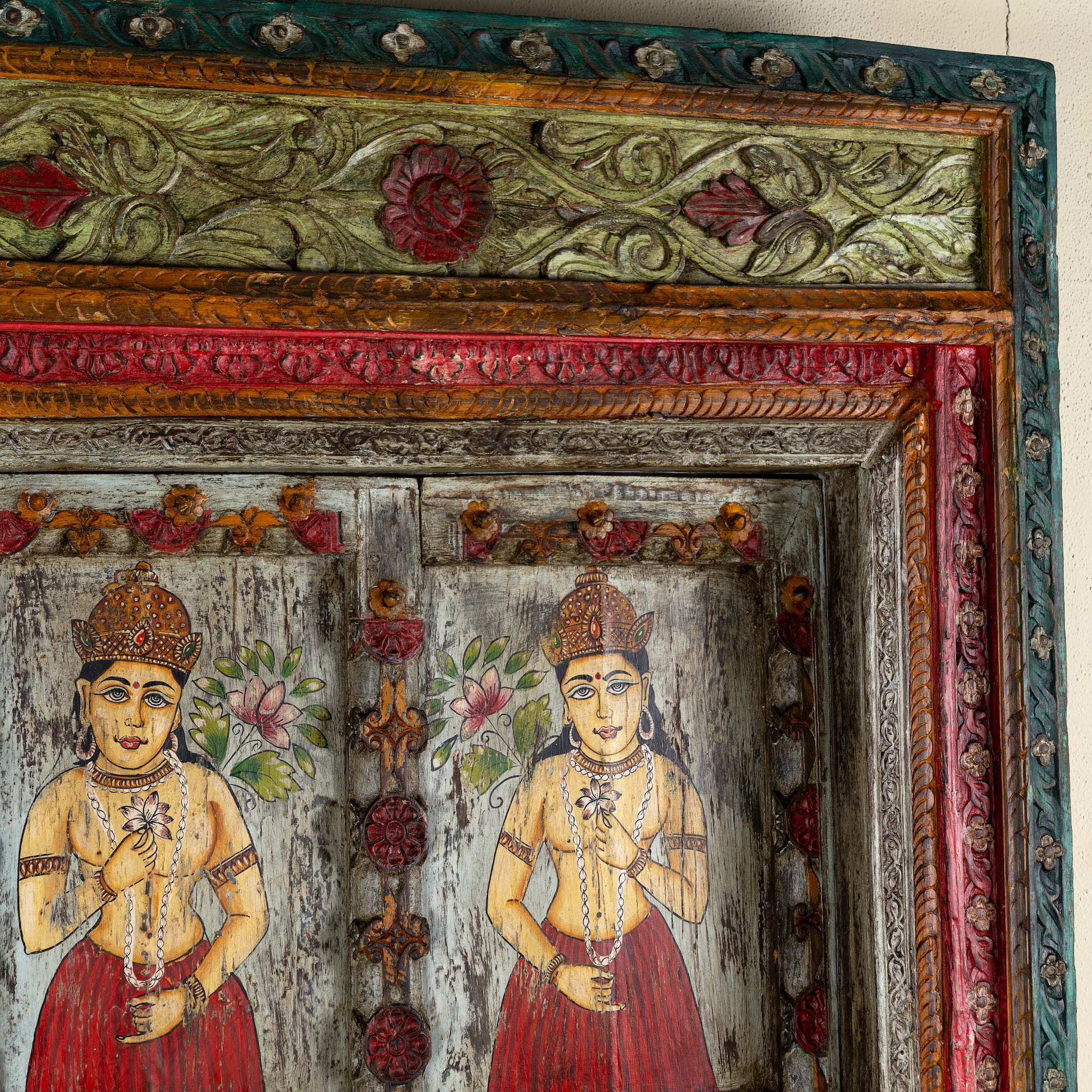 Close up image of an antique Indian teak wood door with hand-painted figures holding lotus flowers, vintage wall panels and vintage home decor.
