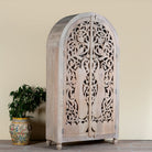 Side angle image of a hand-carved mango wood wardrobe with arched top and intricate peacock floral design – artisanal Indian bedroom furniture.
