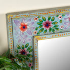 Close up image of a Snehal hand-painted reclaimed wood wall mirror featuring colourful floral artwork and artisan detailing, 90x90cm.