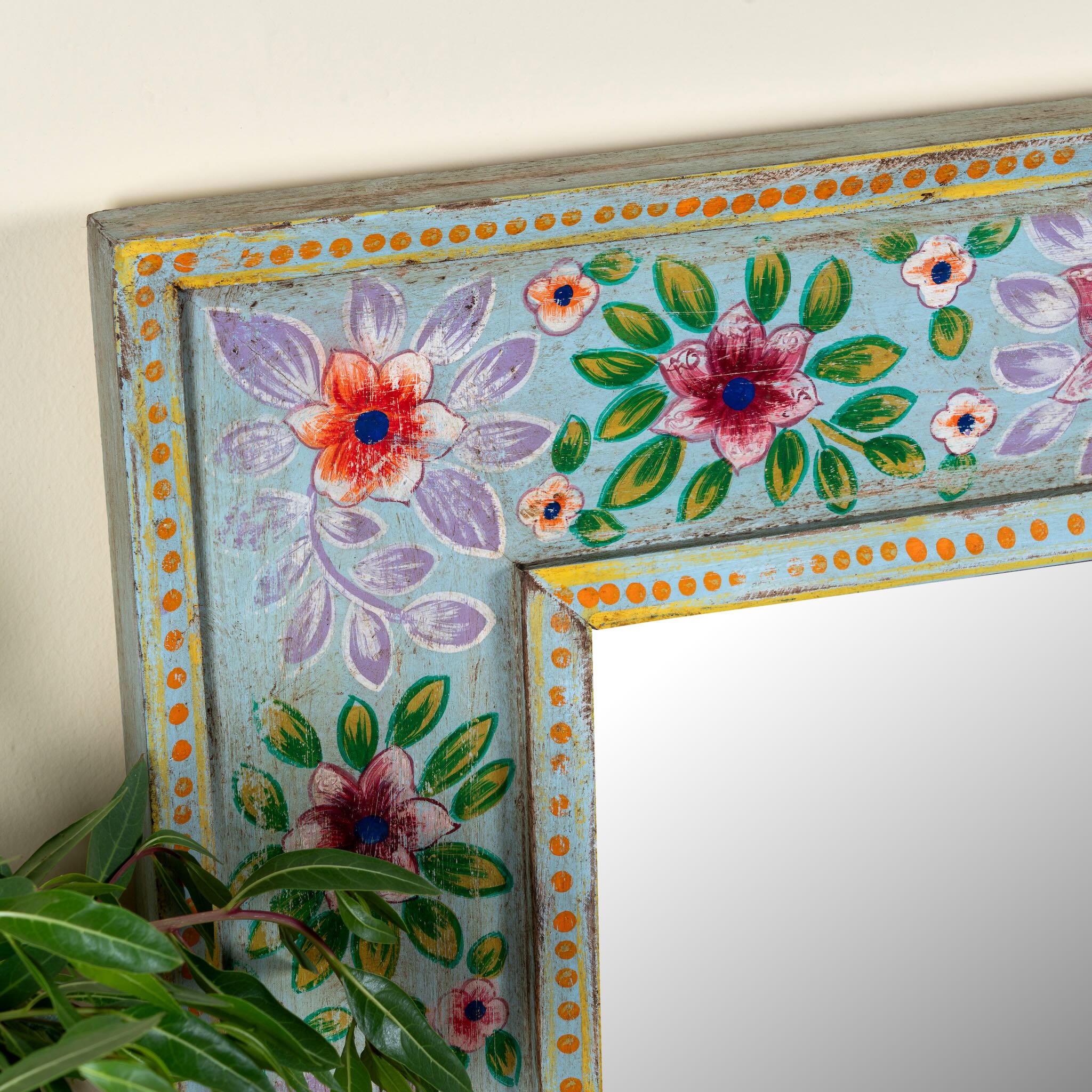 Close up image of a Snehal hand-painted reclaimed wood wall mirror featuring colourful floral artwork and artisan detailing, 90x90cm.