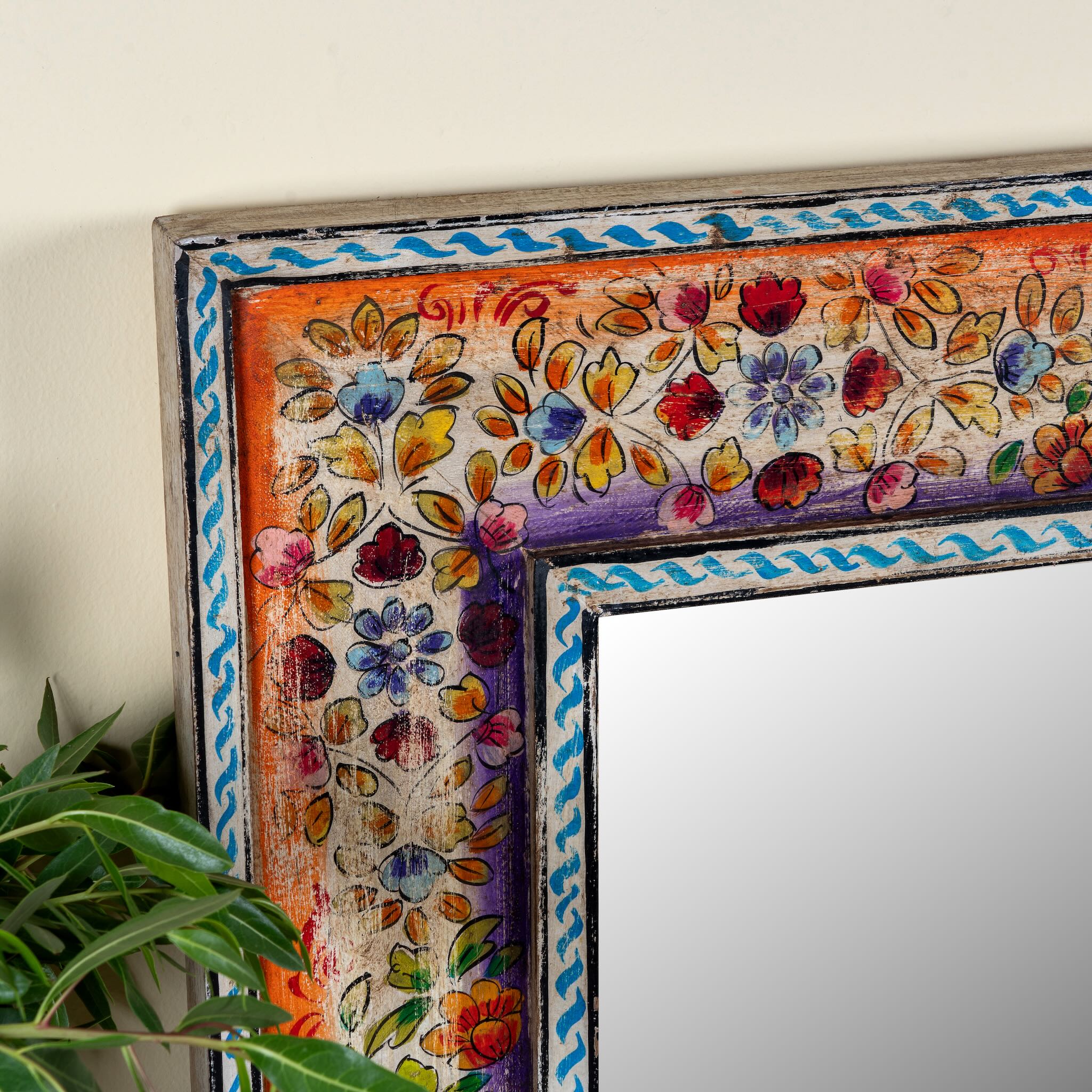 Close up image of a Taksha hand-painted reclaimed wood wall mirror with colourful floral artwork, blue border detailing, and vintage artisan character, 90x90cm.